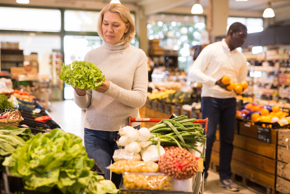 Middle-aged woman shopping for fresh vegetables.