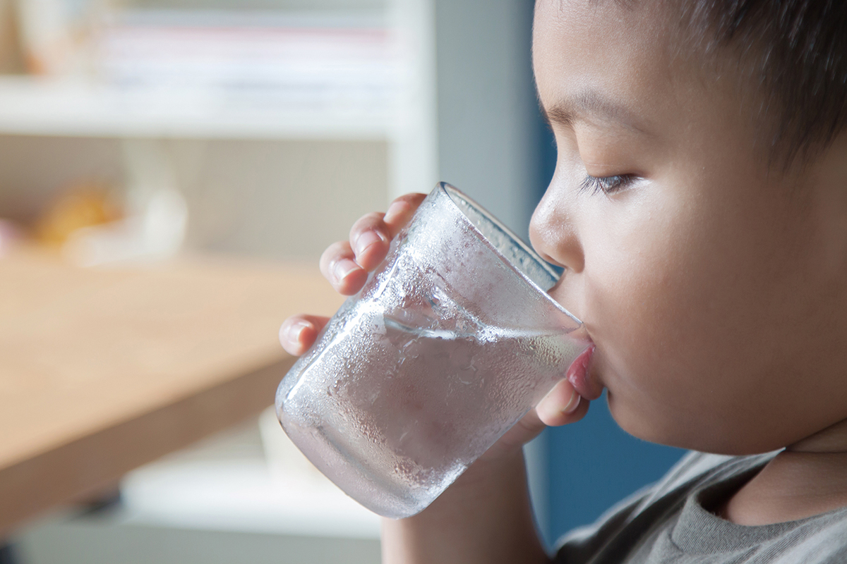 Child drinking a glass of water.