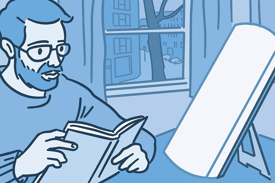 Illustration of a person reading a book while doing light therapy at a table.
